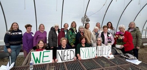 A group of women holding "we need your help" signs.