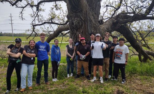 High schoolers pose in front of a large tree.