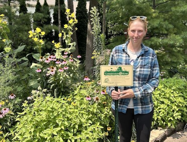 A woman with a sign among native plants.