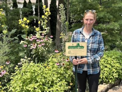 A woman with a sign among native plants.