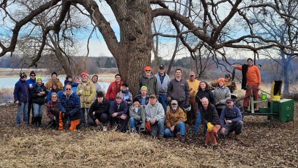 A group posing in front of an oak tree in winter.