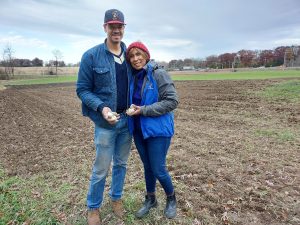 A couple poses in a farm field. 