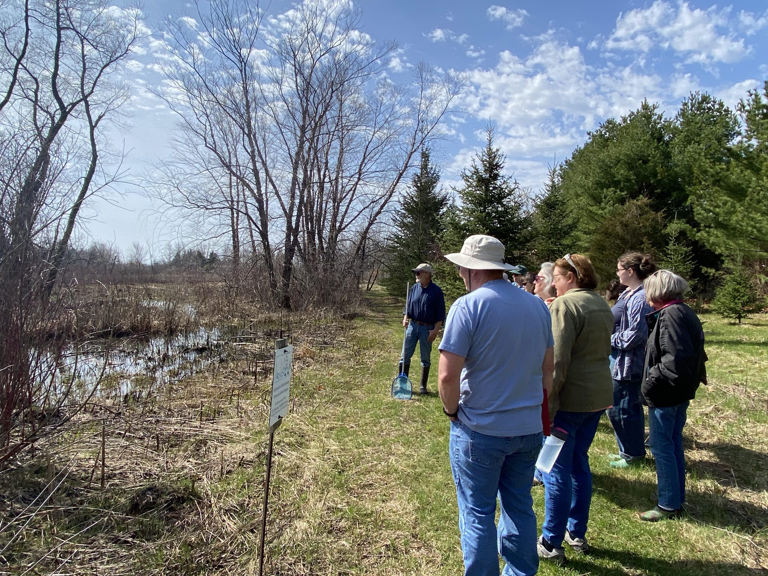 A group of people observes a vernal pool.