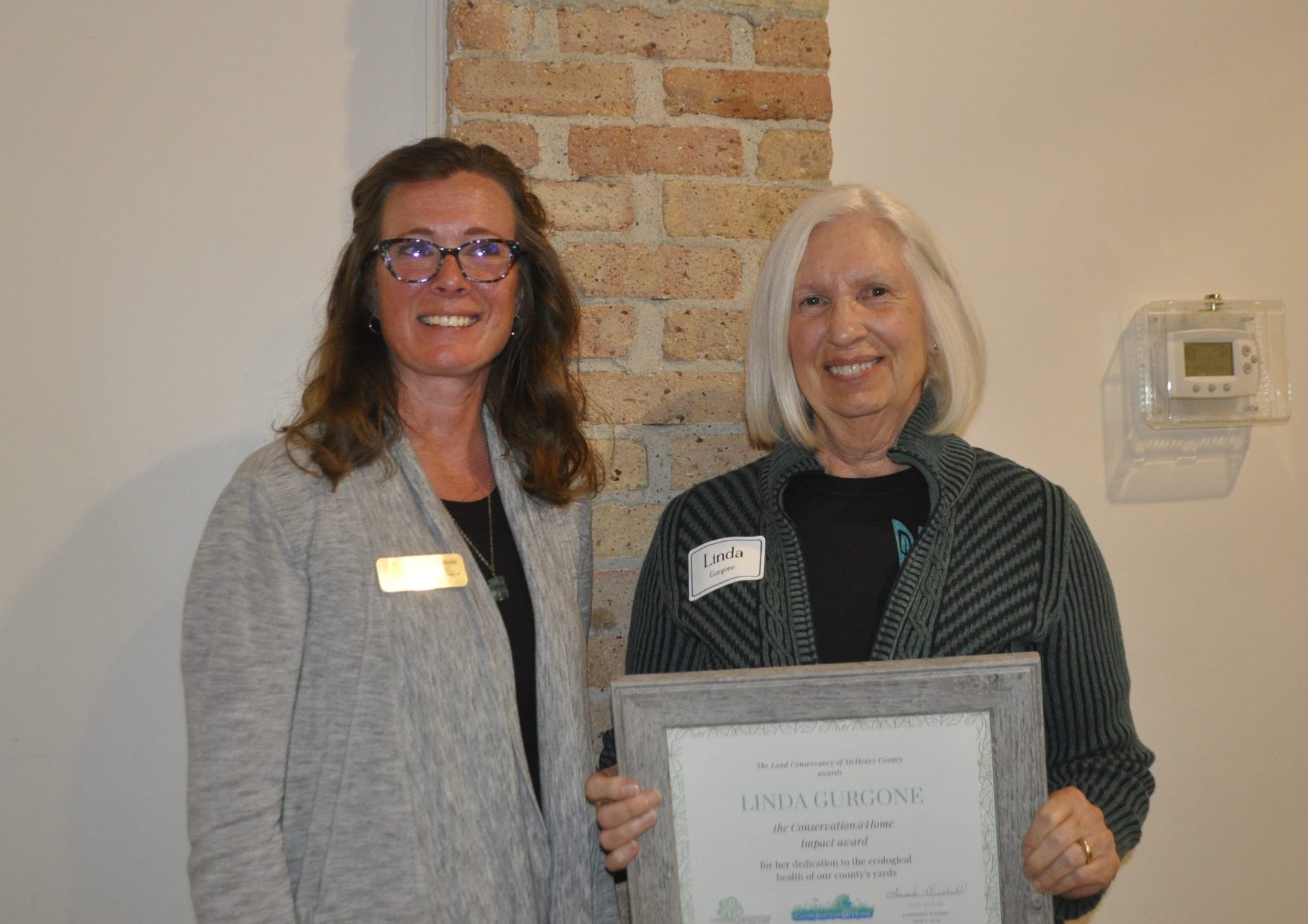 Two people posing and holding an award.