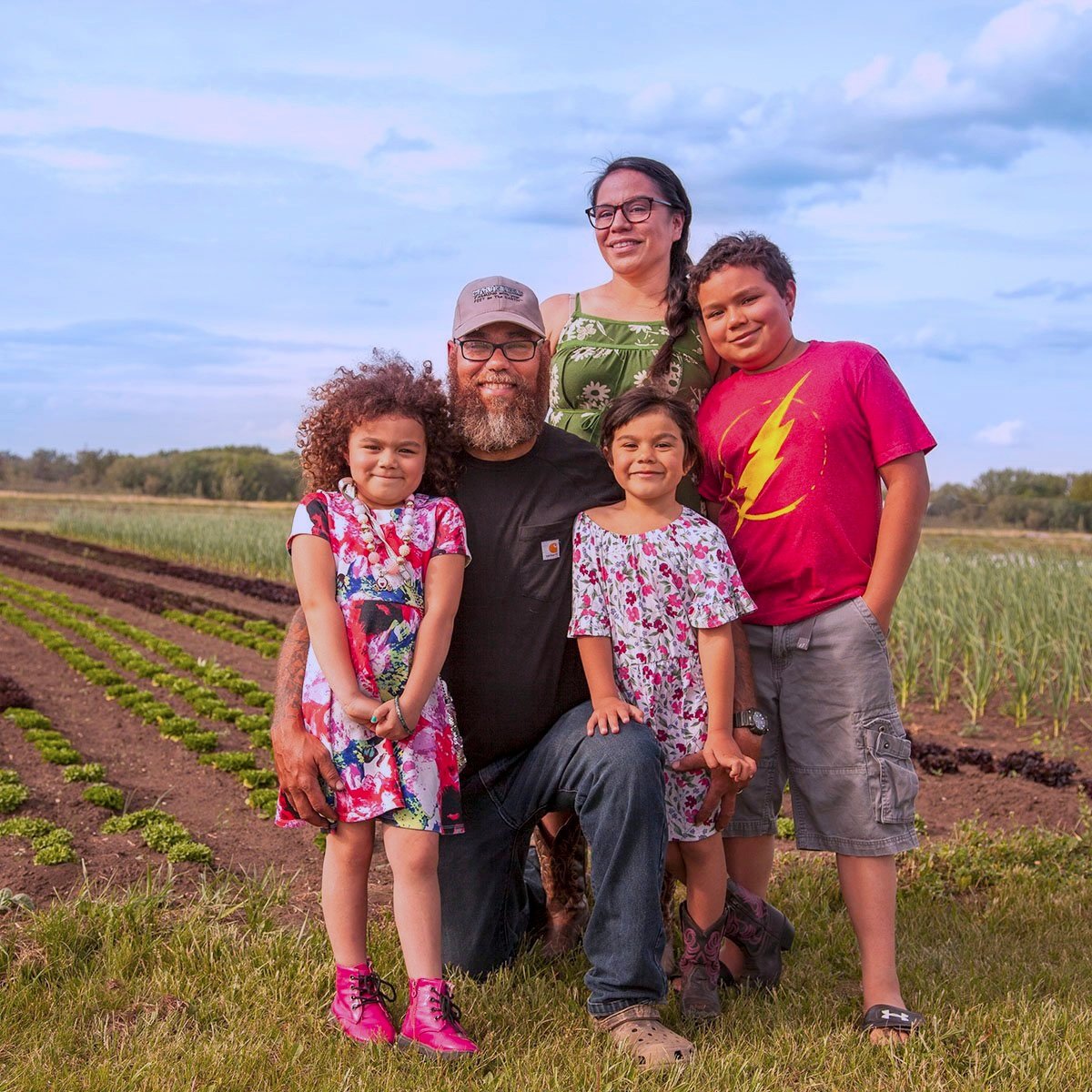 A family of five posing on a farm