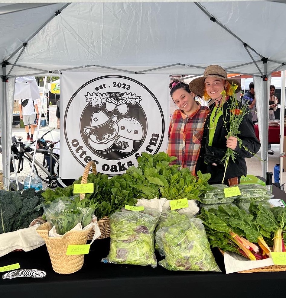 Soraya Alem and Jarvi Schneider under a canopy at a farmer's market table.