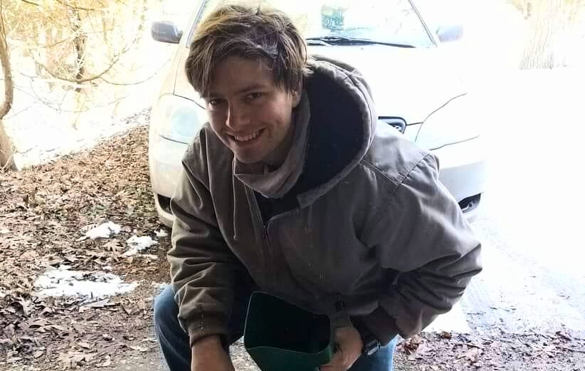TLC member Jacob Karkowski kneeling by buckets of native seed.