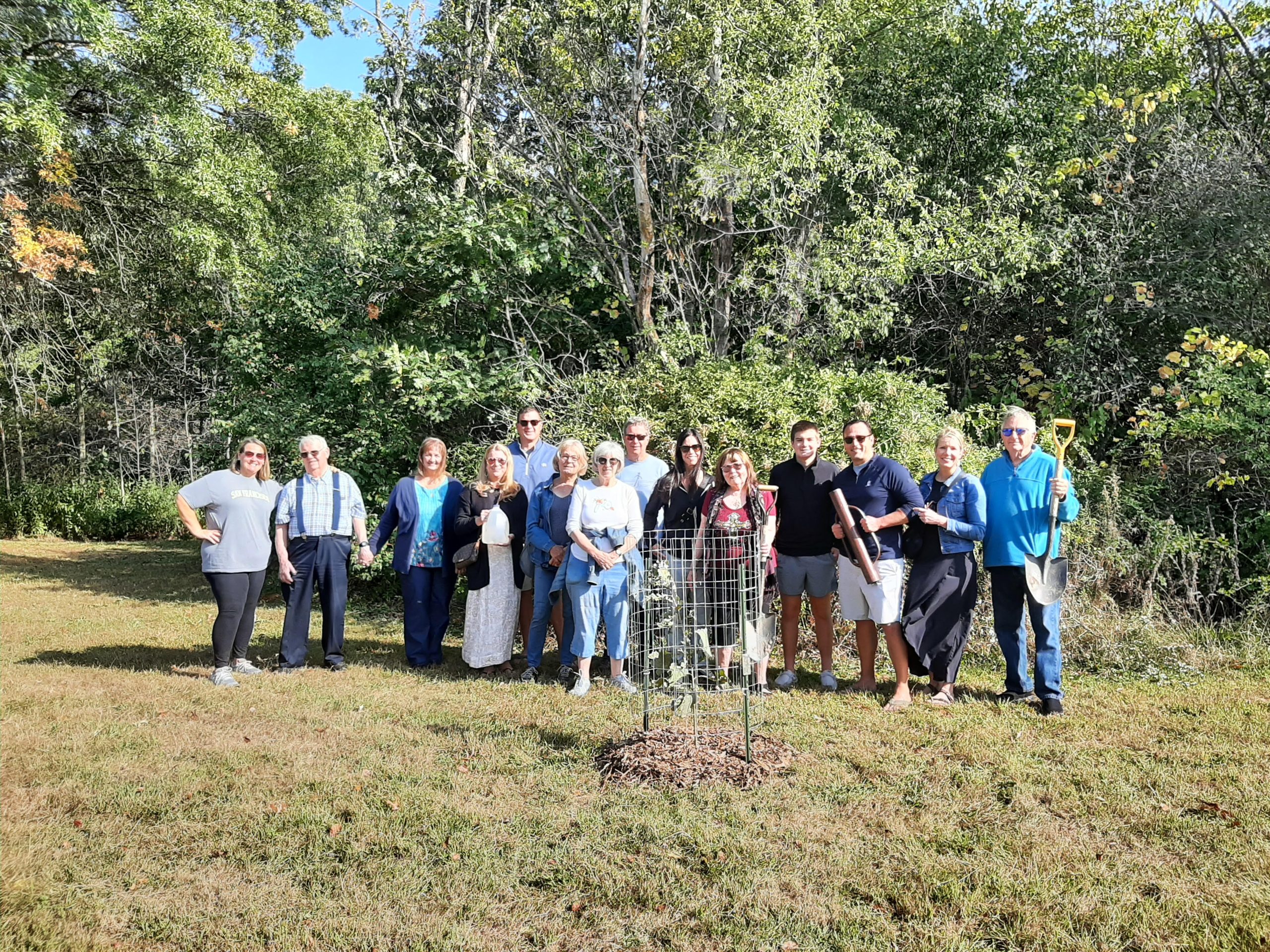 A group o people posing for a photo at an oak planting