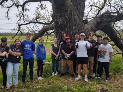High schoolers pose in front of a large tree.