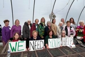 A group of women holding "we need your help" signs.