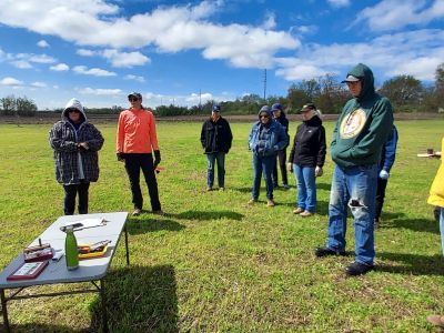 A group of people listening to a speaker outside.