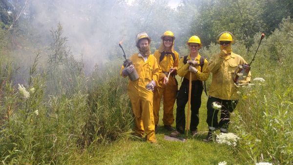 A group of people in protective gear at a controlled burn. 