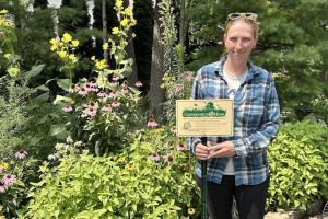 A woman with a sign among native plants.