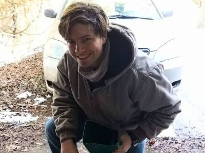 TLC member Jacob Karkowski kneeling by buckets of native seed.